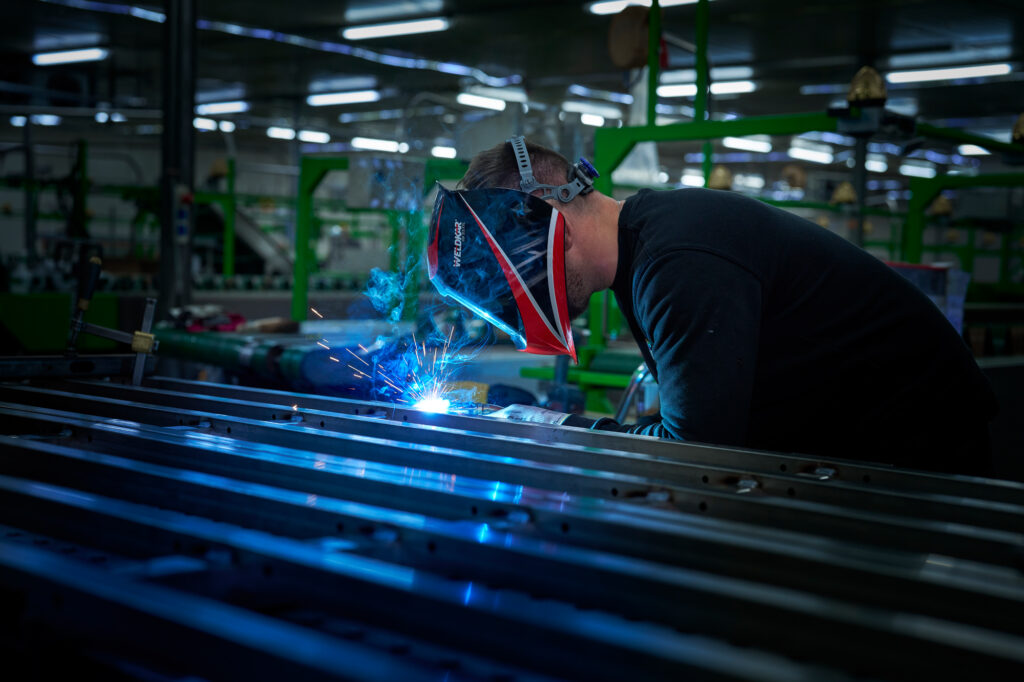 Medewerker van Ruigrok Groep last een metalen constructie in de productiehal, met vonken en blauw licht zichtbaar tijdens het werk